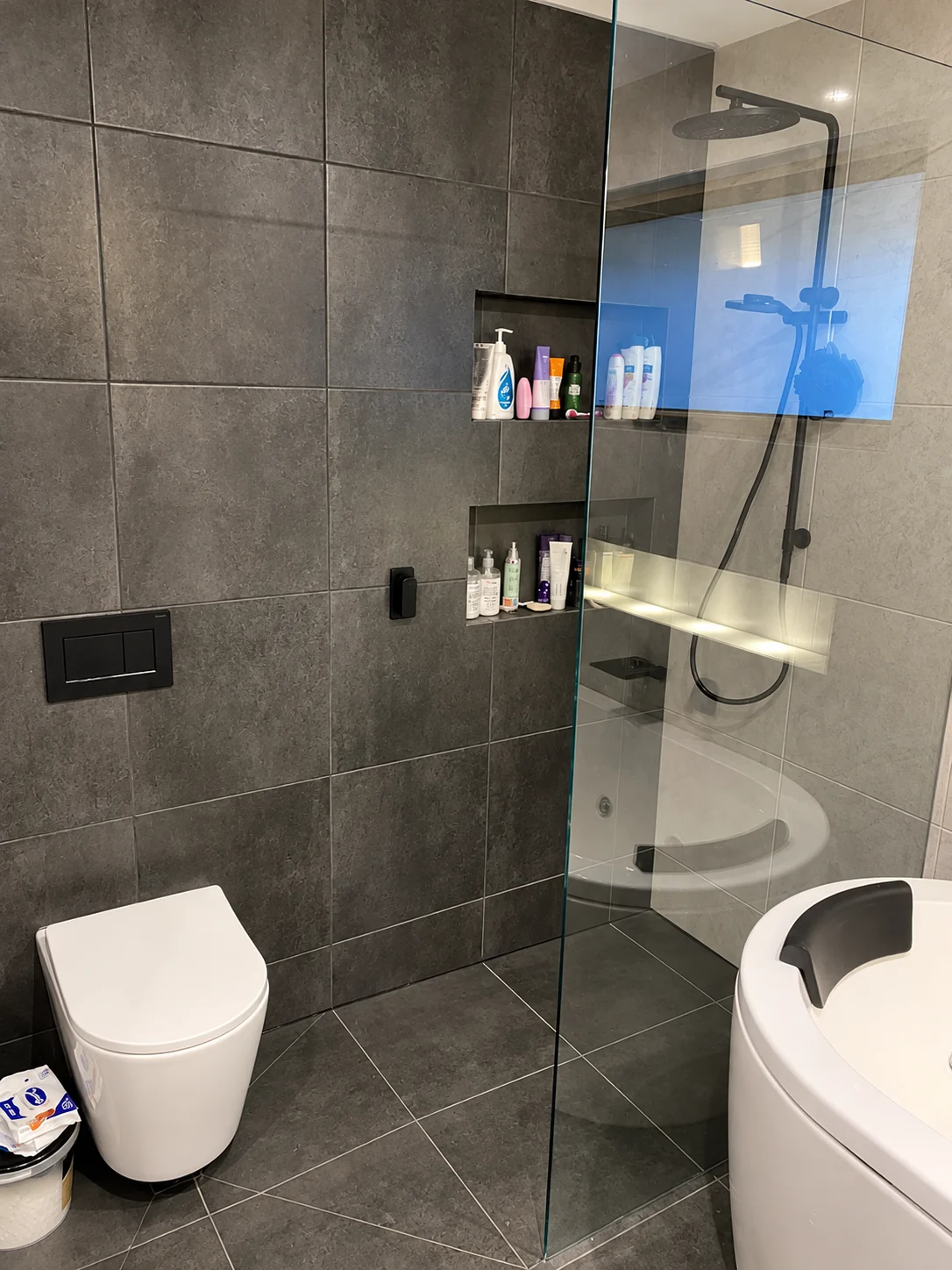 Tiled shower with recessed shelf and glass enclosure.